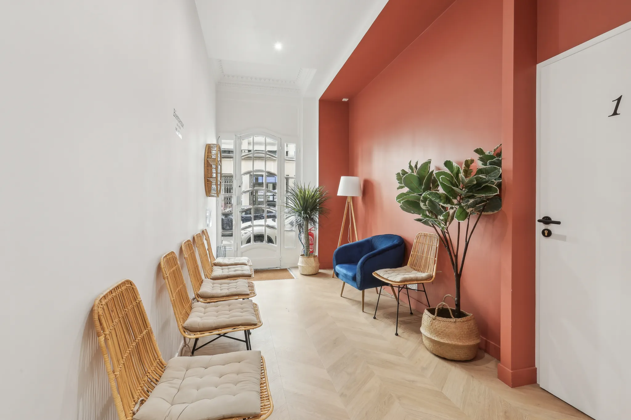 Salle d'attente du cabinet avec fauteuils, plantes et mur terracotta
